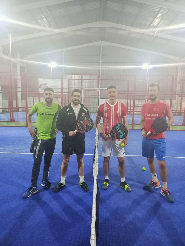 Cuatro jugadores sonríen junto a la red en una pista azul
