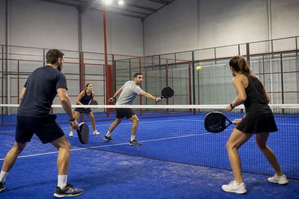 Cuatro jugadores disputan un partido de dobles en una pista indoor